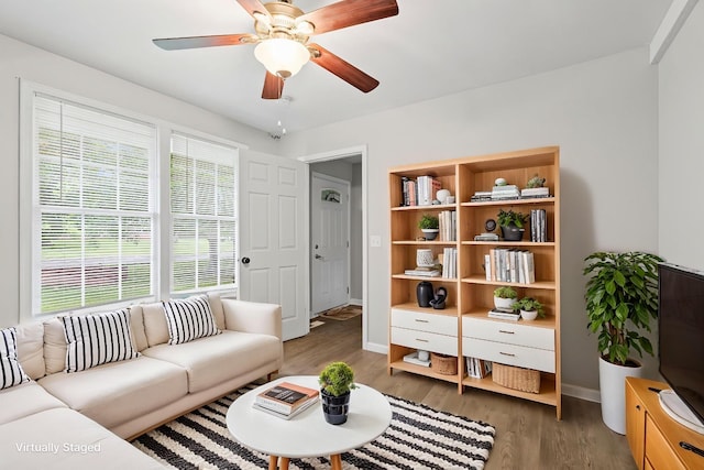 living area featuring baseboards, ceiling fan, and wood finished floors