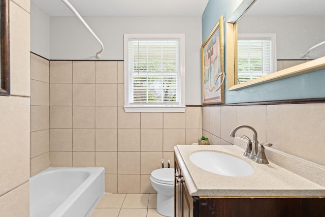 bathroom featuring tile walls, toilet, tile patterned floors, vanity, and a wainscoted wall