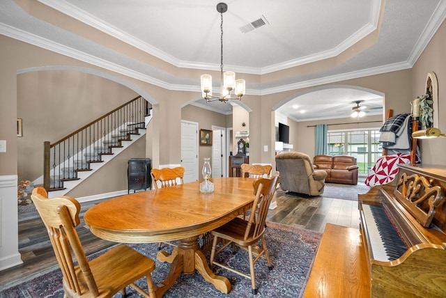 dining space with wood finished floors, ceiling fan with notable chandelier, crown molding, visible vents, and arched walkways