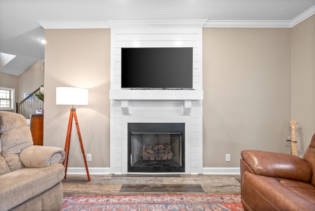 living area with crown molding, baseboards, wood finished floors, and a fireplace