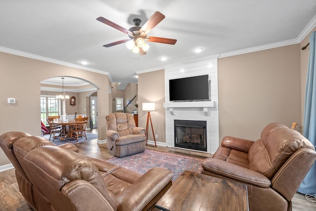 living area featuring arched walkways, crown molding, ceiling fan with notable chandelier, and wood finished floors