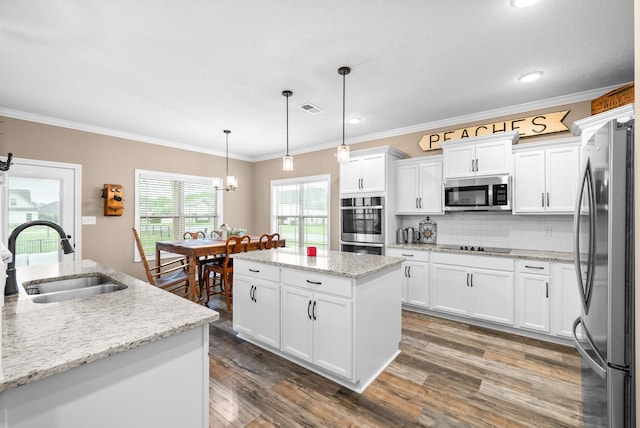 kitchen with a center island, wood finished floors, a sink, visible vents, and appliances with stainless steel finishes