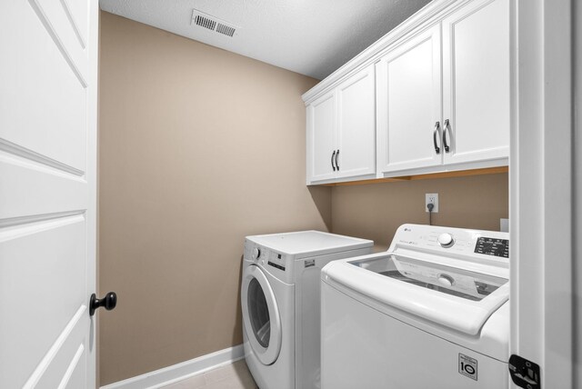clothes washing area featuring cabinet space, visible vents, washer and dryer, and baseboards