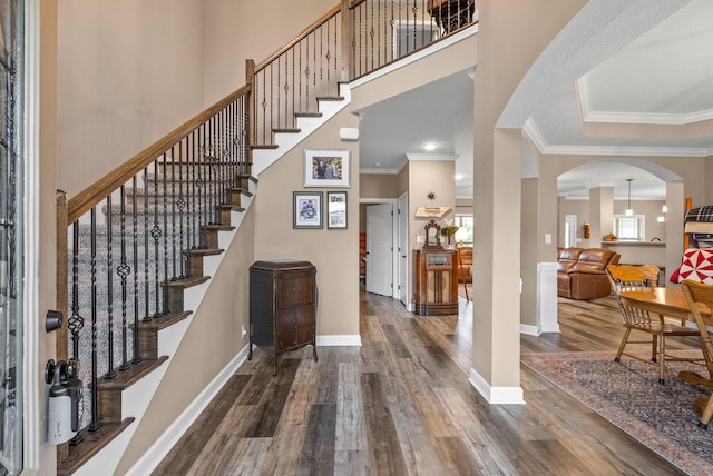 entryway featuring crown molding, a wealth of natural light, arched walkways, and wood finished floors