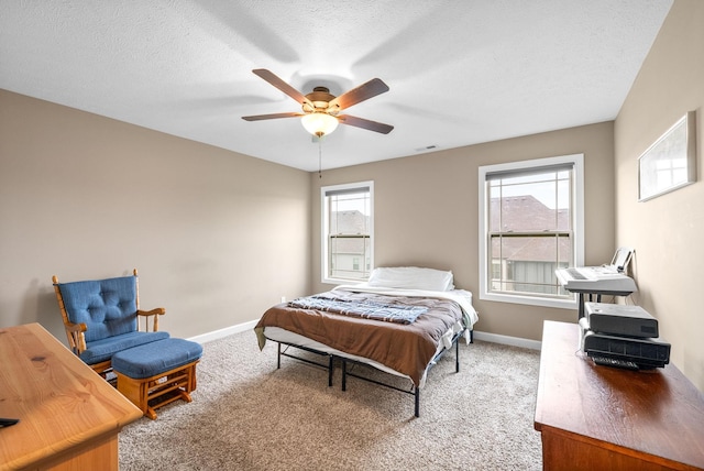 carpeted bedroom featuring a textured ceiling, baseboards, and a ceiling fan