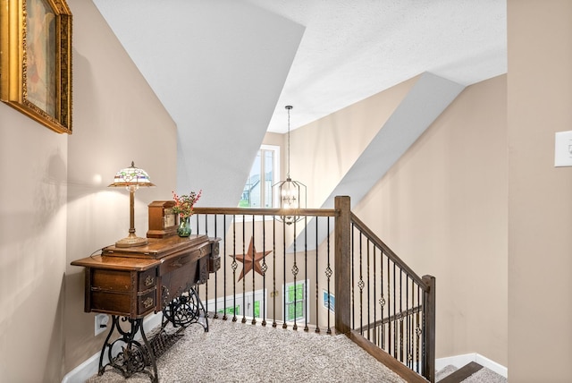hallway featuring carpet, an upstairs landing, baseboards, and a notable chandelier