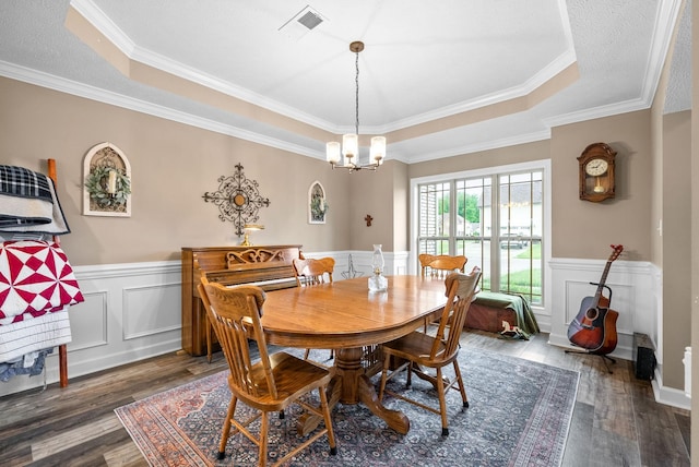 dining room with an inviting chandelier, a tray ceiling, a wainscoted wall, and wood finished floors