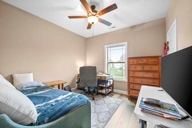 bedroom with light wood finished floors, baseboards, ceiling fan, and visible vents