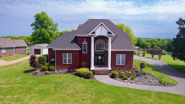 view of front of property with roof with shingles, driveway, brick siding, and a front yard