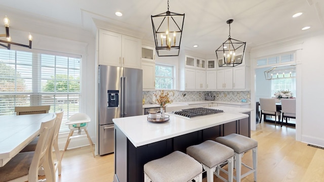 kitchen featuring light wood finished floors, an inviting chandelier, stainless steel appliances, backsplash, and light countertops