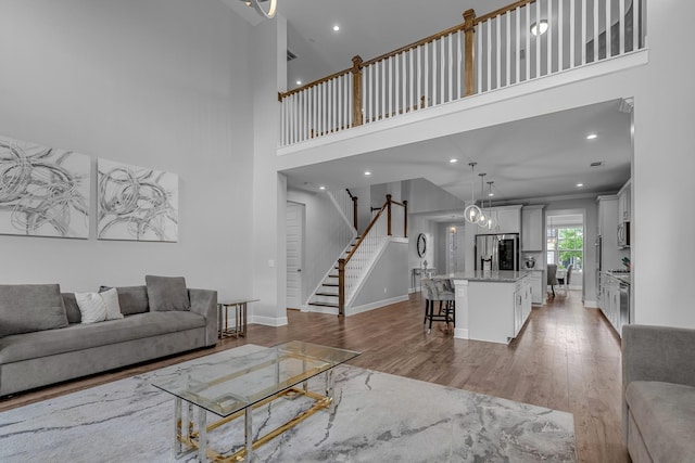 living room with light wood finished floors, stairway, a high ceiling, baseboards, and recessed lighting