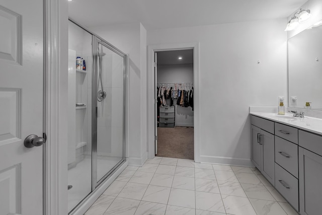 full bath featuring a stall shower, marble look tiles, a spacious closet, and vanity