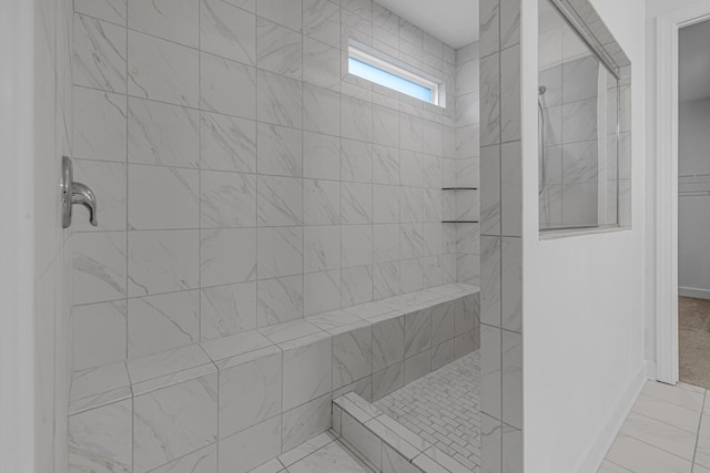 full bath featuring a tile shower and marble look tile flooring