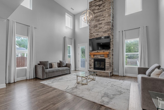 living room featuring a high ceiling, healthy amount of natural light, baseboards, wood finished floors, and a chandelier