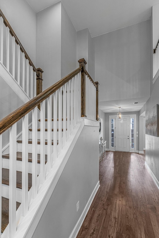 foyer entrance with wood finished floors, baseboards, a high ceiling, and stairs