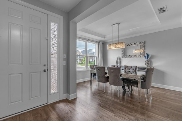 foyer with baseboards, wood finished floors, a raised ceiling, and ornamental molding