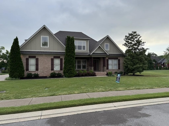 craftsman house featuring board and batten siding, a front yard, and brick siding