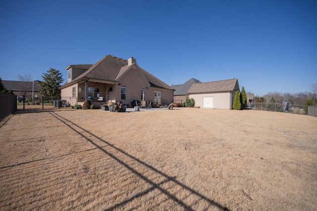 back of house with a chimney, fence, and brick siding