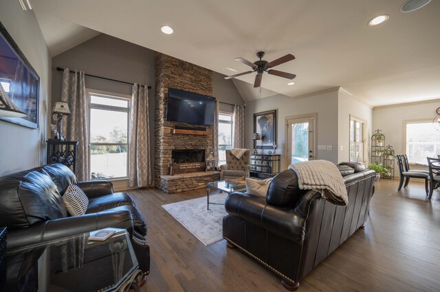 living room with lofted ceiling, a ceiling fan, healthy amount of natural light, dark wood finished floors, and a stone fireplace