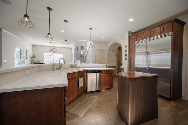 kitchen featuring stainless steel appliances, a sink, a kitchen island, dark wood finished floors, and ornamental molding