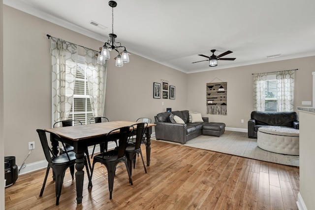 dining space featuring light wood finished floors, a ceiling fan, ornamental molding, a chandelier, and baseboards