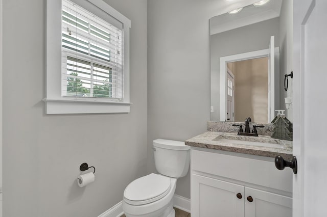 half bath featuring toilet, vanity, and baseboards