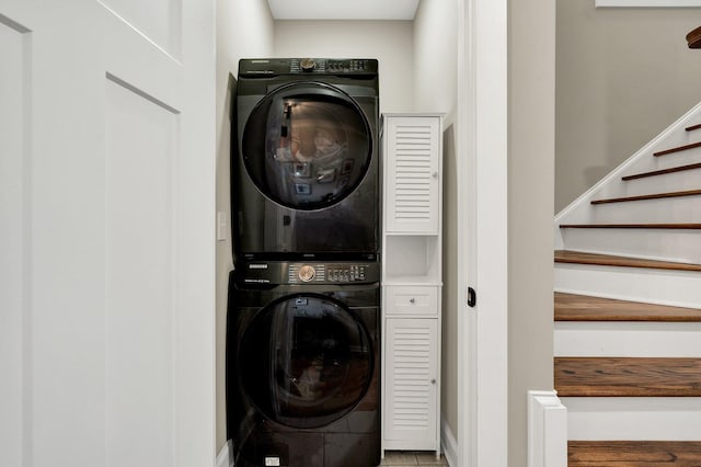 laundry room featuring stacked washer / dryer and baseboards