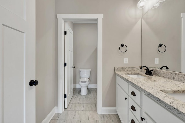 bathroom featuring double vanity, toilet, and baseboards