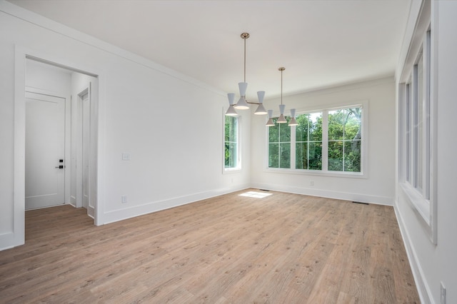 spare room with plenty of natural light, light wood-style flooring, baseboards, and ornamental molding