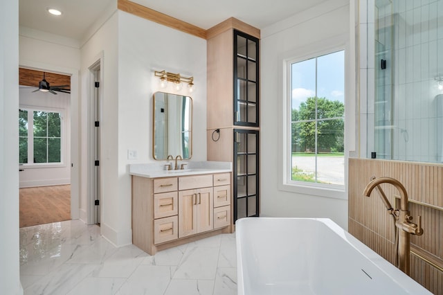 bathroom with plenty of natural light, a freestanding tub, vanity, and marble finish floors