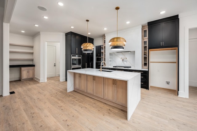 kitchen featuring a sink, oven, cooktop, dark cabinetry, and light stone countertops