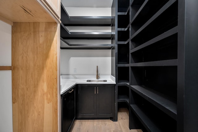 walk in closet featuring light wood-style flooring and bar with sink