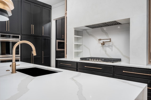 kitchen with a sink, dark cabinets, stainless steel appliances, and wall chimney range hood