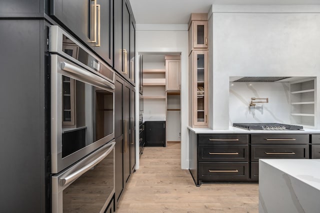 kitchen with appliances with stainless steel finishes, light wood-type flooring, open shelves, and glass insert cabinets