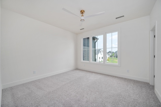 spare room featuring light carpet, baseboards, and a ceiling fan