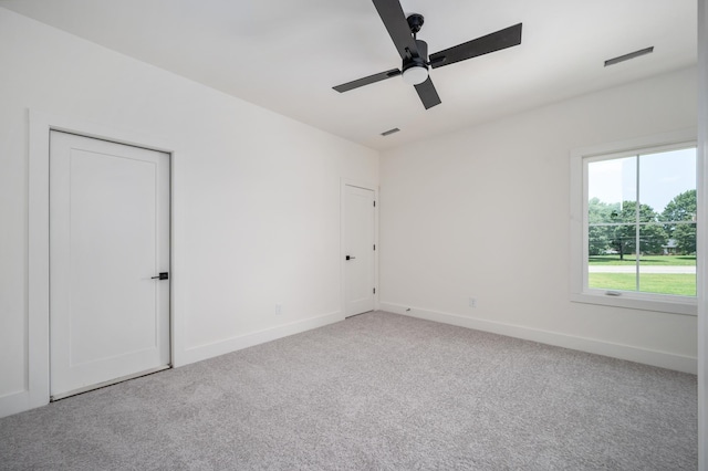 spare room with carpet floors, a ceiling fan, and baseboards