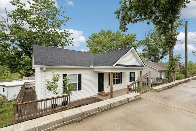 view of front facade featuring a shingled roof and a deck