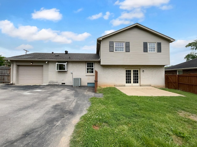 back of property with an attached garage, brick siding, driveway, a patio area, and french doors