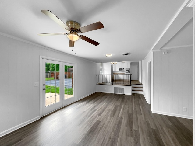 unfurnished living room featuring ornamental molding, dark wood-type flooring, baseboards, ceiling fan, and a decorative wall