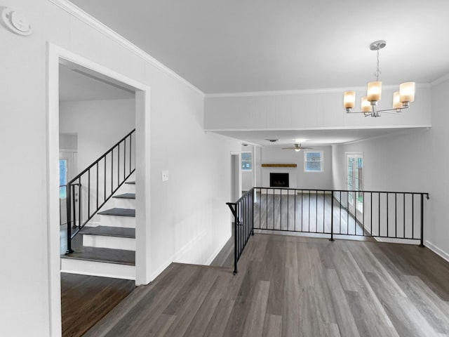 unfurnished room featuring wood finished floors, ornamental molding, a smoke detector, baseboards, and a ceiling fan