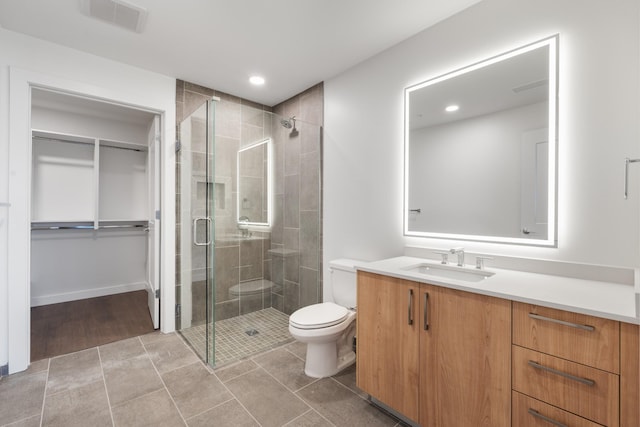 full bath with a stall shower, toilet, a spacious closet, vanity, and recessed lighting