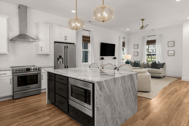 5615 Tennessee Ave Unit A, Nashville, TN 37209 - kitchen featuring premium appliances, wall chimney range hood, open floor plan, white cabinets, and recessed lighting