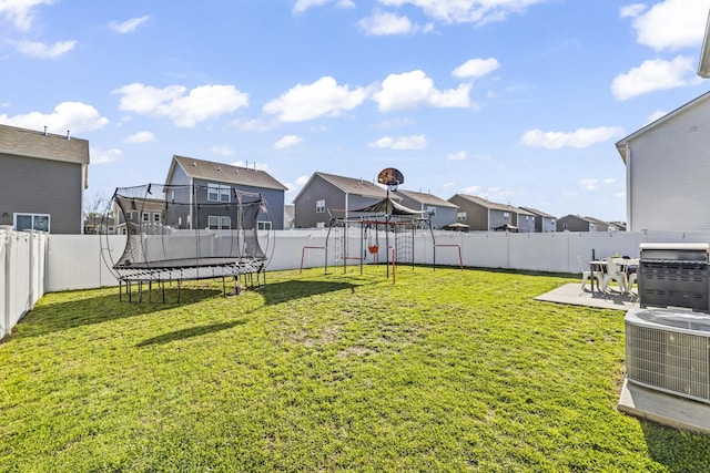view of yard featuring a residential view, a trampoline, and central AC unit