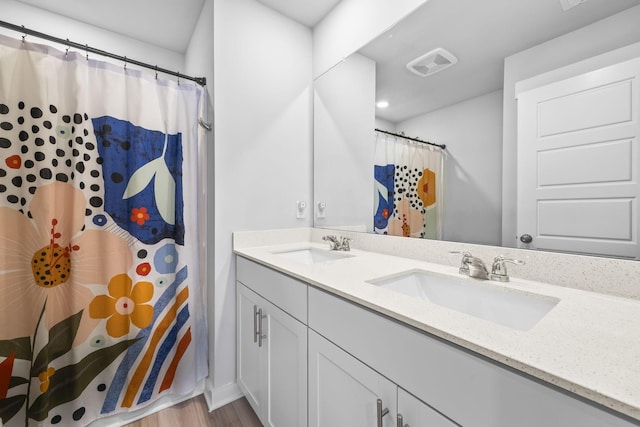 full bathroom featuring wood finished floors, double vanity, a shower with shower curtain, and baseboards