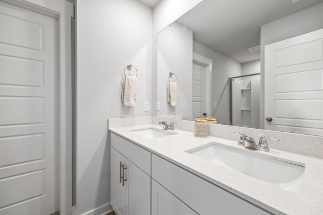 bathroom featuring a shower, double vanity, and baseboards