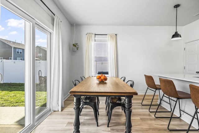 dining area with light wood-type flooring, healthy amount of natural light, and baseboards