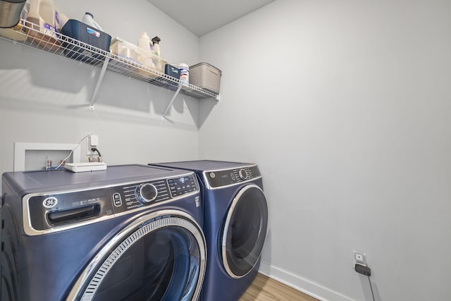 washroom with separate washer and dryer, baseboards, and wood finished floors