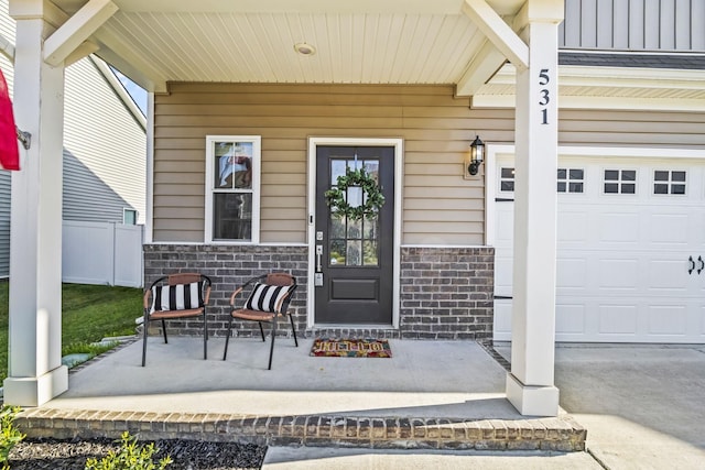 property entrance featuring a porch, stone siding, and a garage