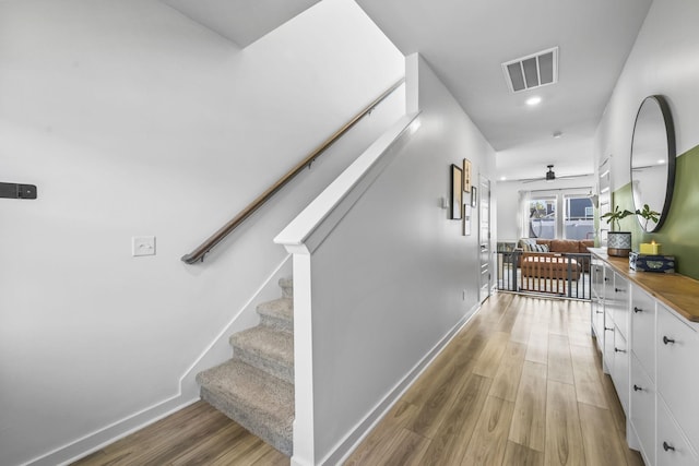 hallway featuring light wood-type flooring, stairs, and baseboards