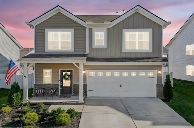 view of front of house with covered porch, driveway, an attached garage, a shingled roof, and board and batten siding